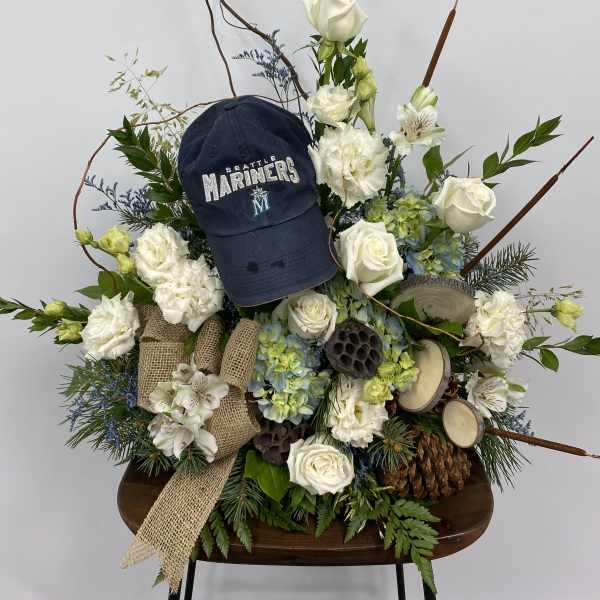 Floral arrangement with white roses, hydrangeas, and a Seattle Mariners cap