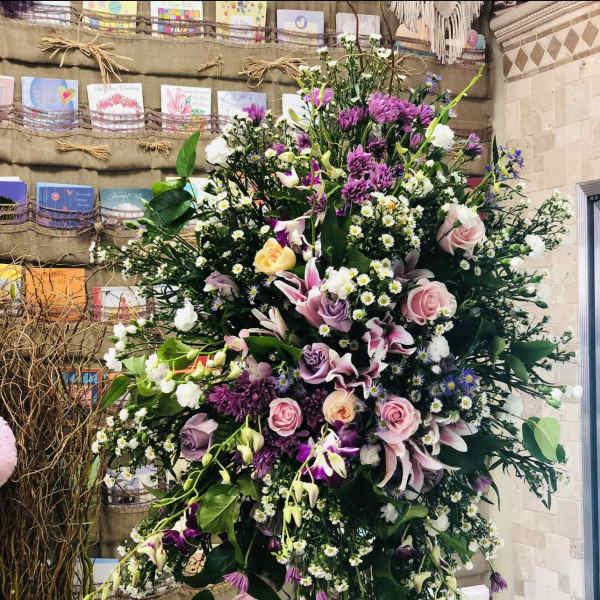 Large standing floral spray with pink, purple, and white blooms