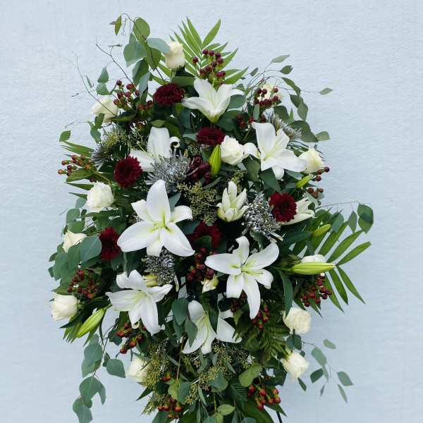 Standing floral spray with white lilies and roses on a black easel