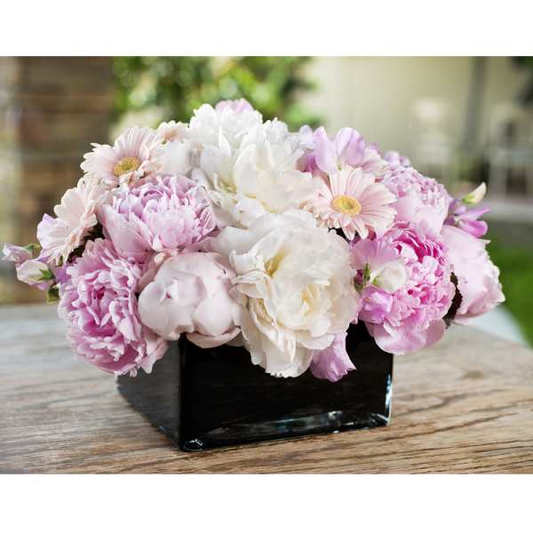 Pink and white flowers arranged in a black square vase