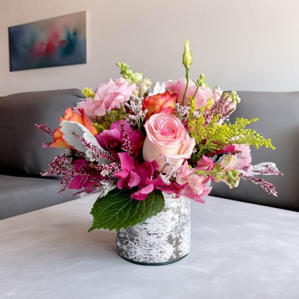 Pink and peach floral arrangement in a white textured vase
