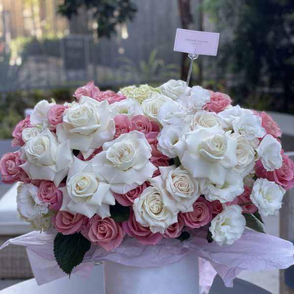 Pink and white rose arrangement in a white hatbox