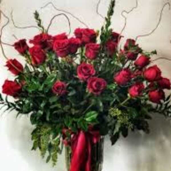 Red roses arranged in a tall vase with a red ribbon