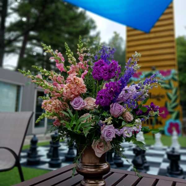 Tall bouquet of pink, lavender, and purple flowers in a bronze vase