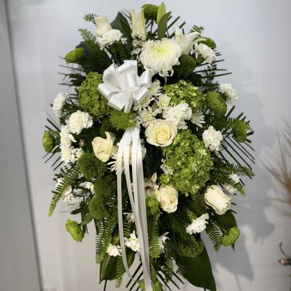 White and green funeral spray with roses and chrysanthemums on a stand