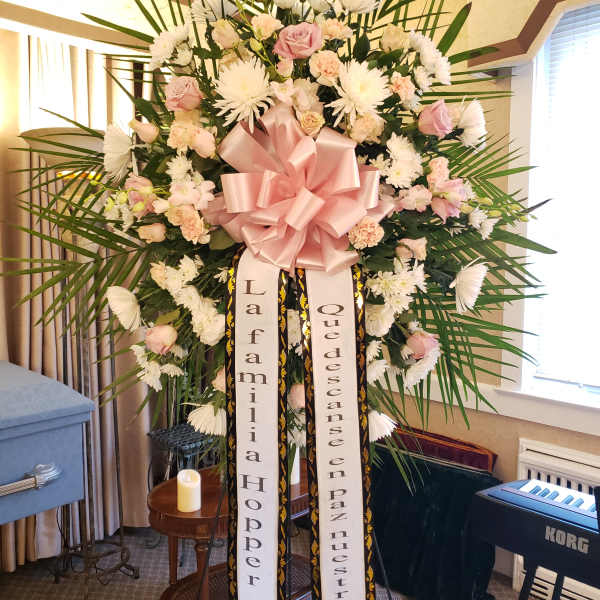 Large standing floral spray with pink and white flowers and a pink bow