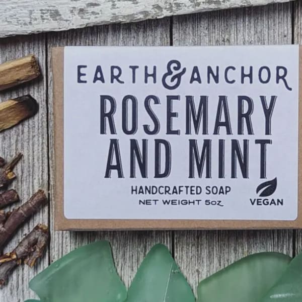 Bar of rosemary and mint handcrafted soap with white label on rustic wood background