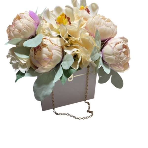 Cream and blush floral arrangement in a gift bag with a chain handle