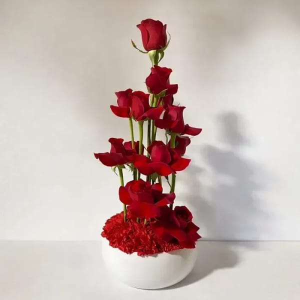 Tall arrangement of red roses in a white vase