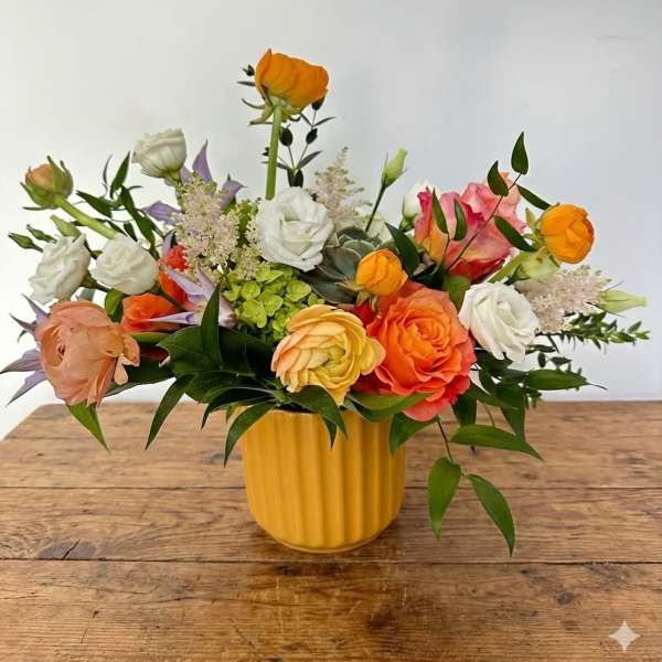 Mixed bouquet of orange, white, and pink flowers in a yellow vase