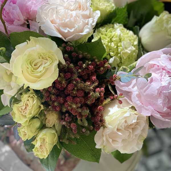 Arrangement of blush roses, green hydrangea, and pink peonies in a vase