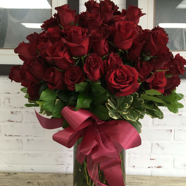 Bouquet of red roses in a glass vase with a burgundy ribbon