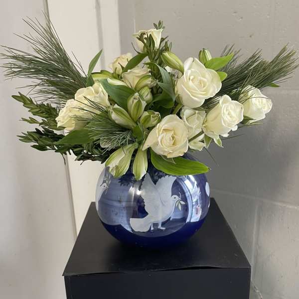 White roses and lilies arranged in a blue glass vase