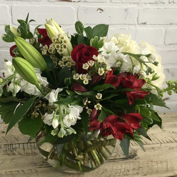 Bouquet of red roses, white lilies, and white hydrangeas in a glass vase