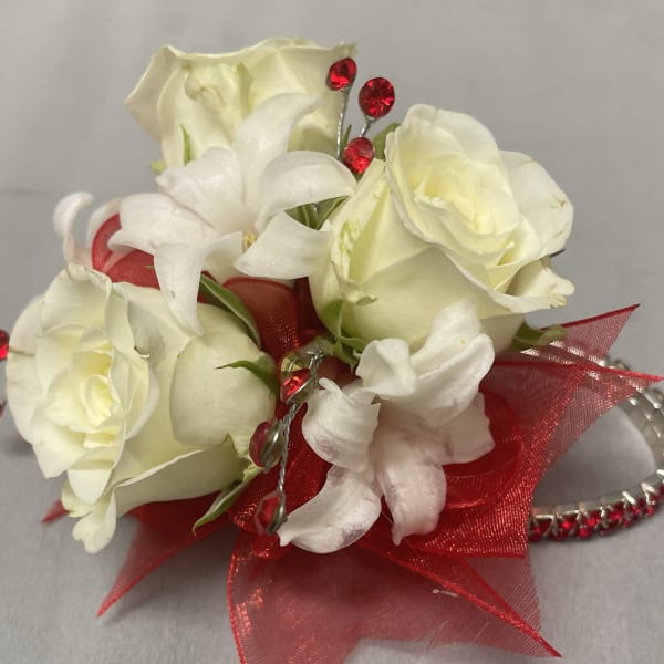 White rose wrist corsage with red ribbon and red rhinestones on a silver bracelet