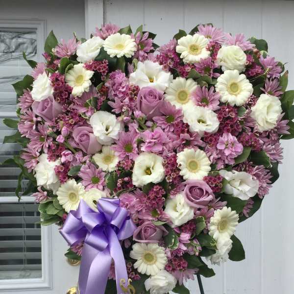 Heart-shaped pink and white floral standing spray with a purple ribbon