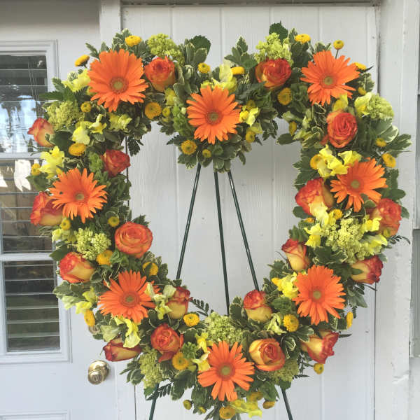 Heart-shaped floral wreath with orange gerberas and roses on an easel