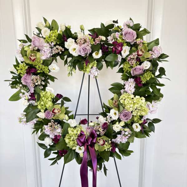 Heart-shaped floral wreath on an easel with a purple ribbon