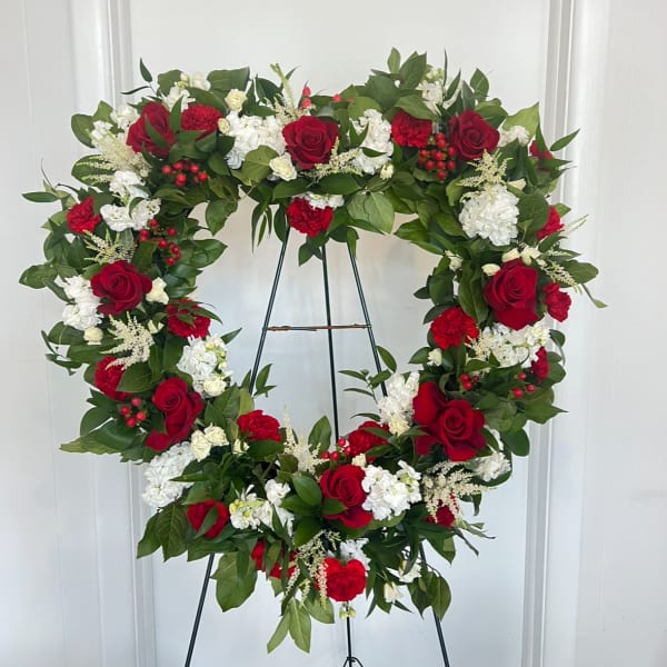 Heart-shaped wreath of red and white flowers on a stand