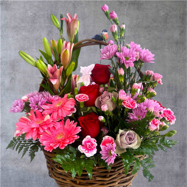 Mixed pink and red flowers in a wicker basket