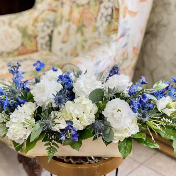 White and blue floral arrangement in a low container