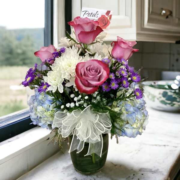 Pink roses and white chrysanthemums in a glass vase with a ribbon bow