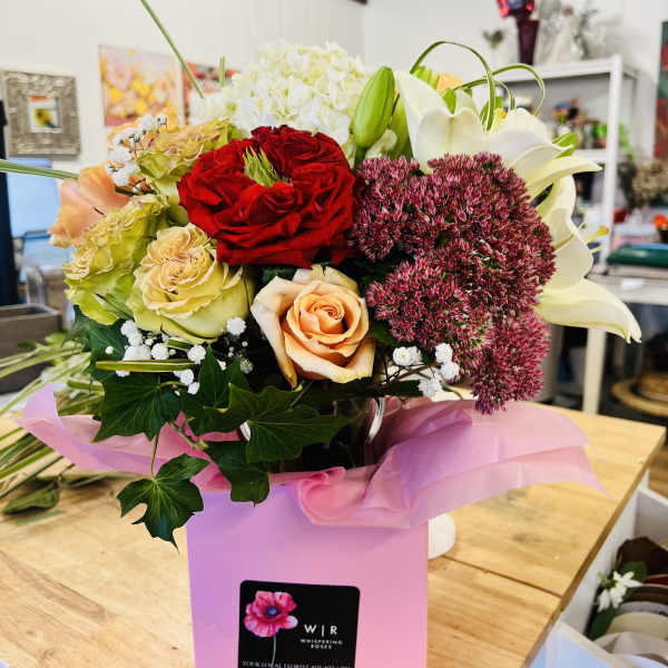 Mixed bouquet of roses, lilies, and hydrangea in a pink box