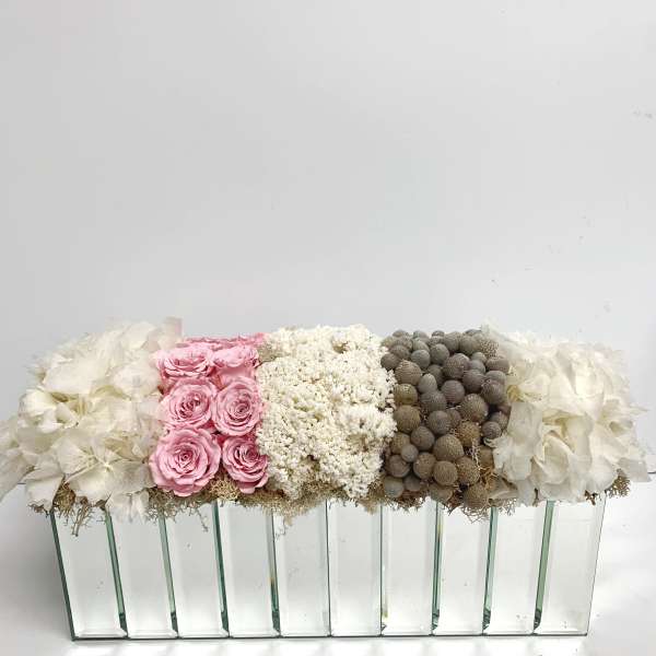 Pink roses and white flowers arranged in a long glass vase.