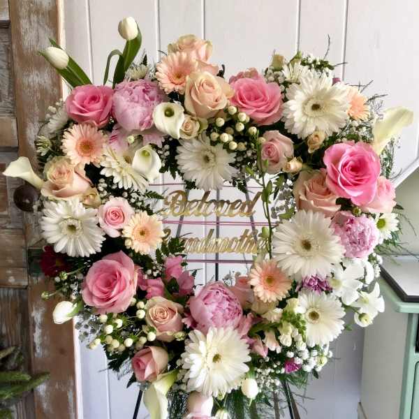 Heart-shaped floral wreath with pink and white flowers on an easel