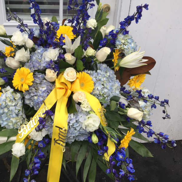 Large floral spray with blue, white, and yellow flowers and yellow ribbons