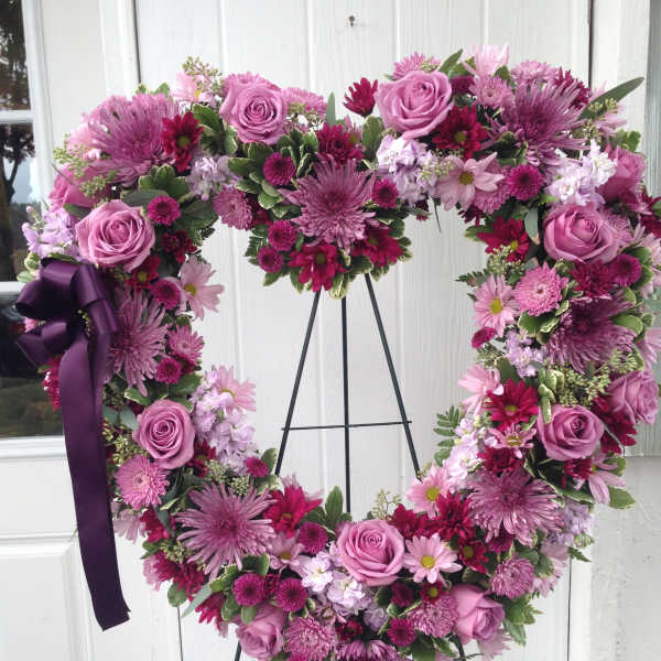 Heart-shaped floral wreath with pink and purple blooms on a stand