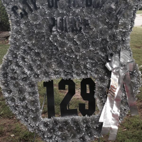 Large silver floral tribute with "City of Hoboken Police" and "129" lettering