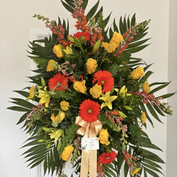 Large standing floral spray with red gerberas, yellow roses, and lilies