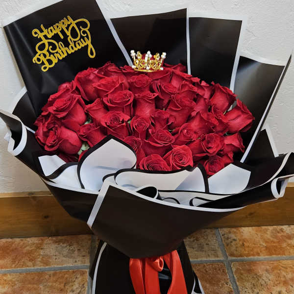 Bouquet of red roses in black and white wrap with a birthday topper
