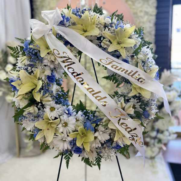 Floral wreath with white and blue flowers and yellow lilies on an easel