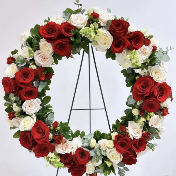 Circular wreath of red and white roses on a black stand