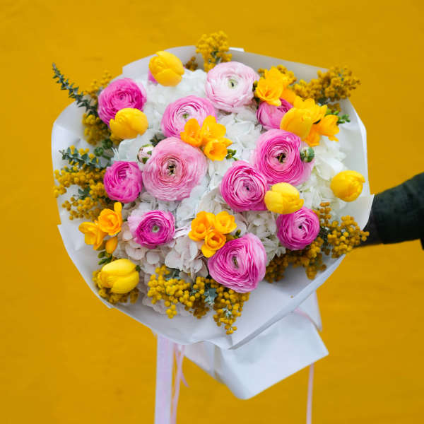 Bouquet of pink and yellow flowers wrapped in white paper