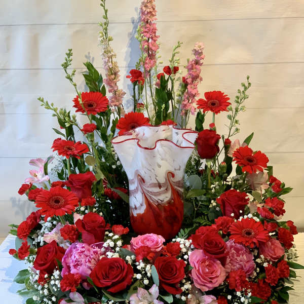Large red and pink floral arrangement in a marbled vase
