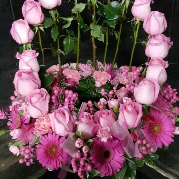 Pink roses arranged in a heart shape with pink daisies at the base