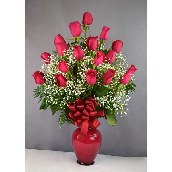 Pink roses arranged in a red vase with a red bow