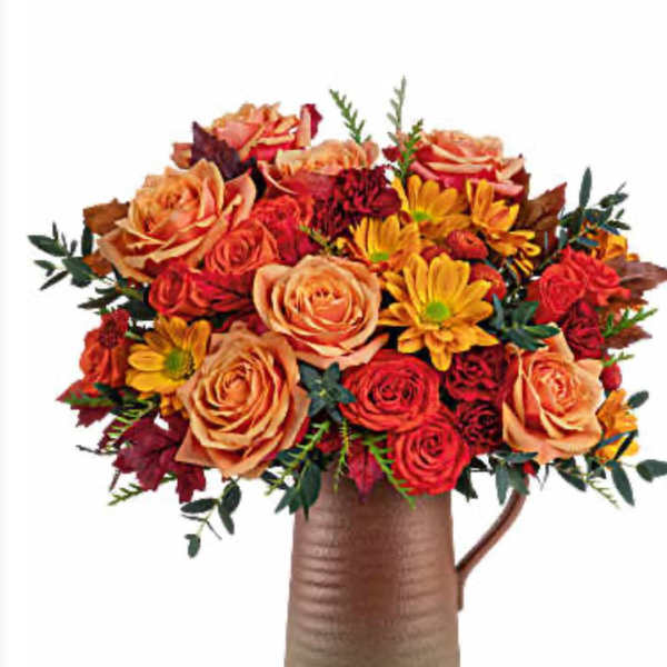 Bouquet of orange and red flowers in a brown pitcher vase