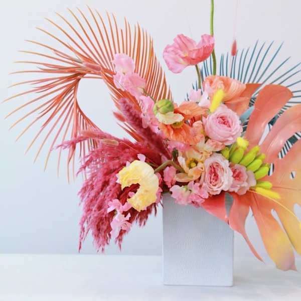 Colorful floral arrangement in a white vase with pink and peach blooms