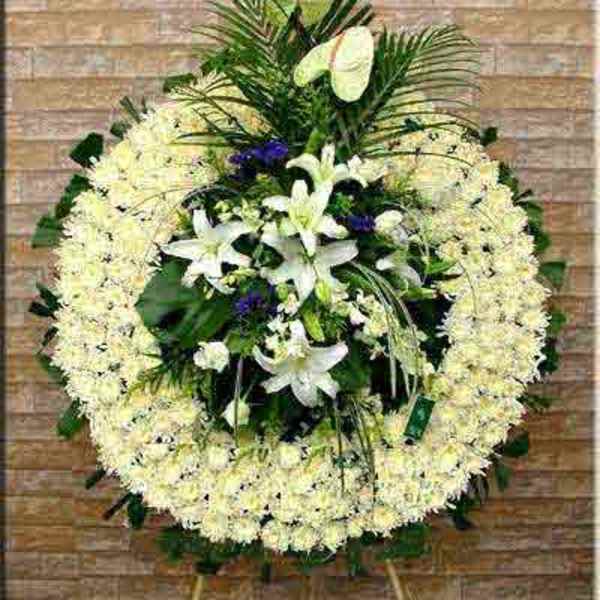 Large standing floral wreath with white lilies and pale blooms on an easel
