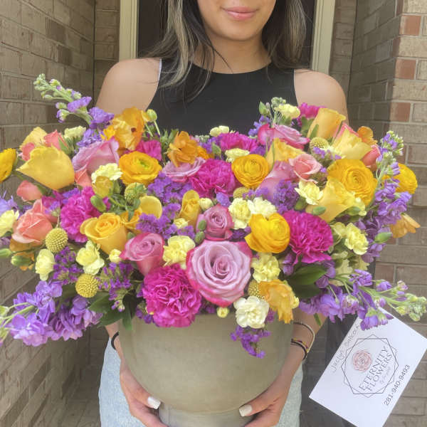 Large mixed bouquet in a beige hatbox with pink, yellow, and purple flowers