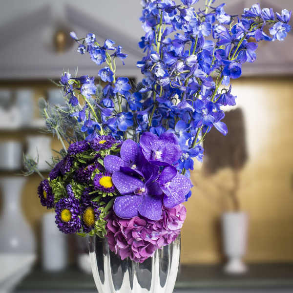 Purple and blue floral arrangement in a silver vase