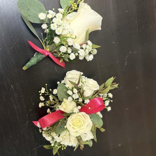 Two white rose boutonnieres with baby's breath and pink ribbon