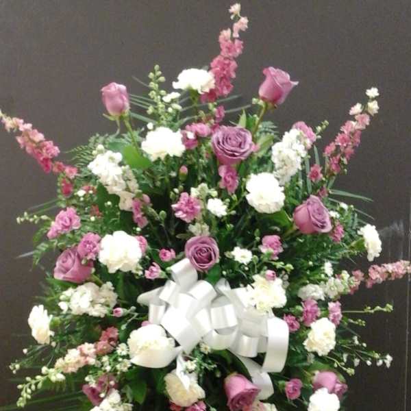 Large standing floral spray with pink and white flowers and a white ribbon bow
