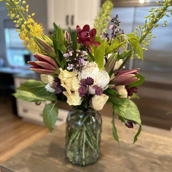 Mixed bouquet in a glass vase with lilies, orchids, and pale blooms