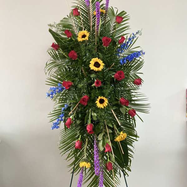 Tall standing floral spray with red roses, sunflowers, and purple spikes