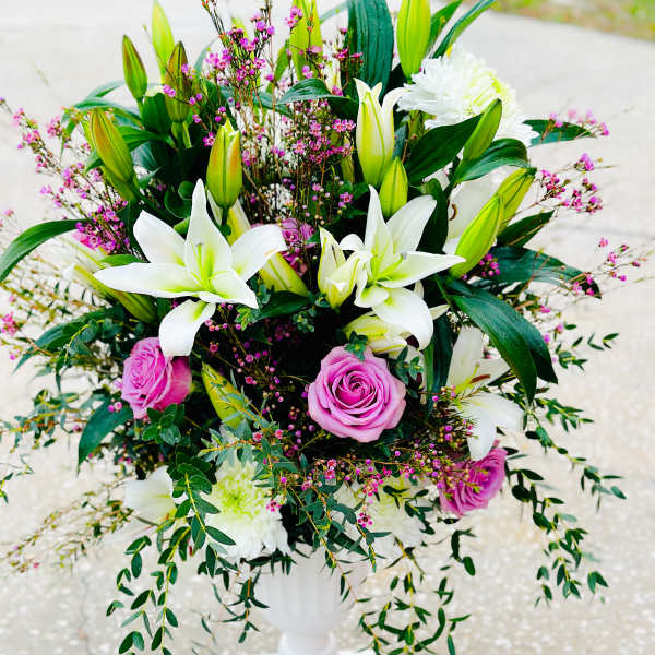 White lilies and pink roses arranged in a white pedestal vase